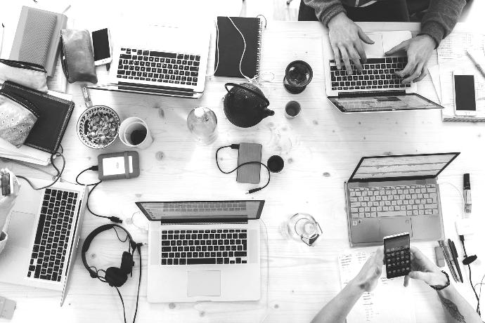 people sitting down near table with assorted laptop computers